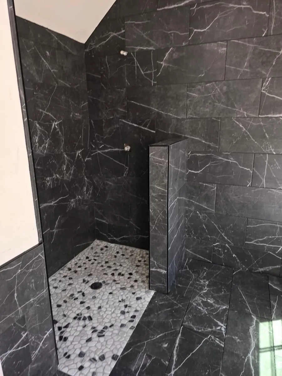Black marble walk-in shower with pebble stone floor